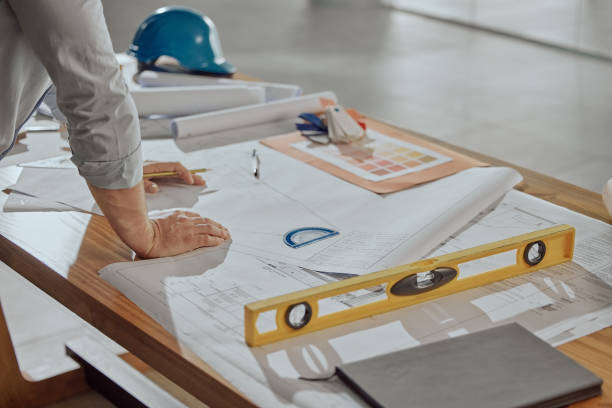 Architect, hands and planning on blueprint for construction or preparation for building on office desk. Hand of engineer in architectural design for project, floor plan or industrial layout strategy